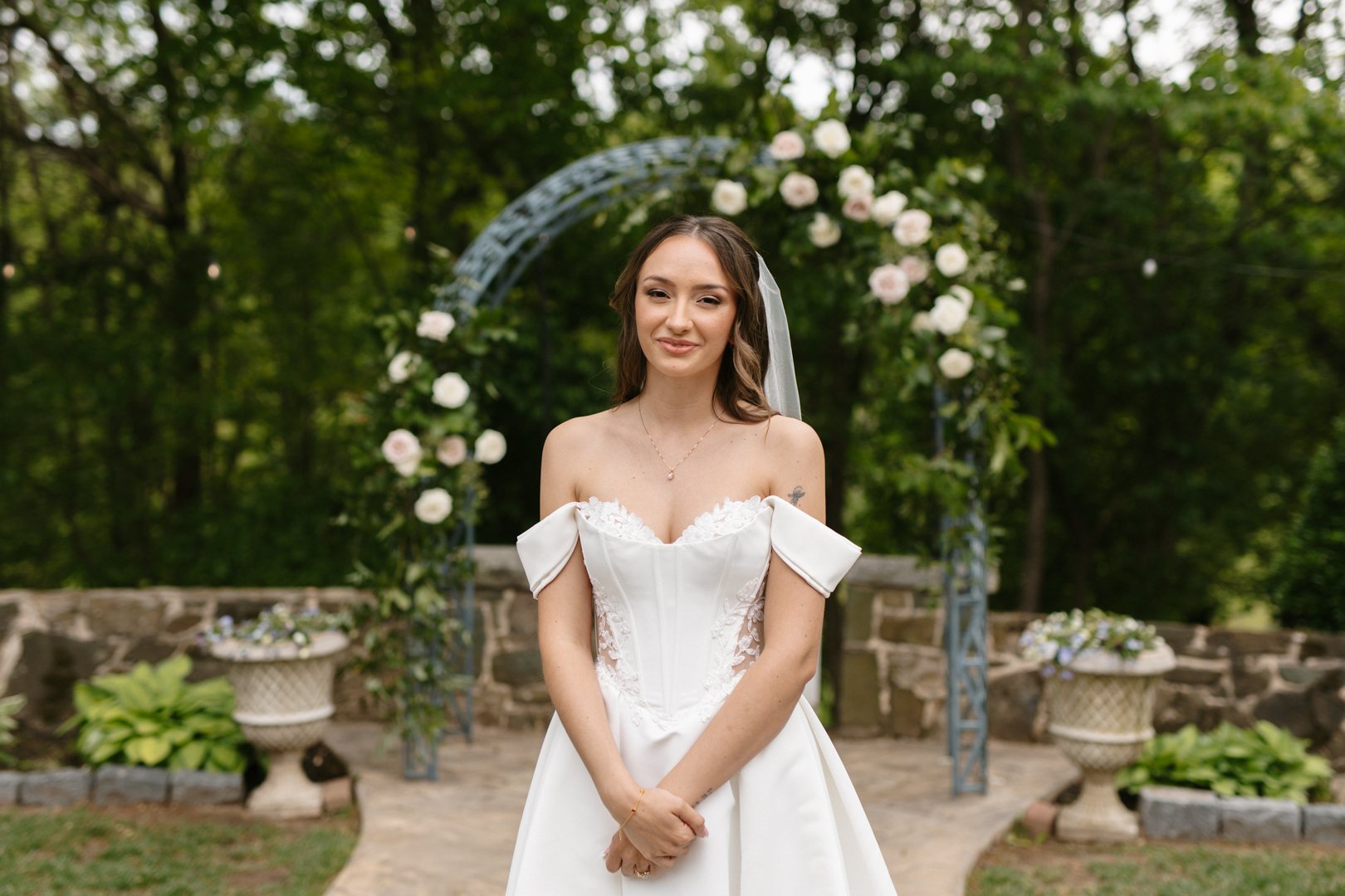 Bride standing before a floral ceremony arch
